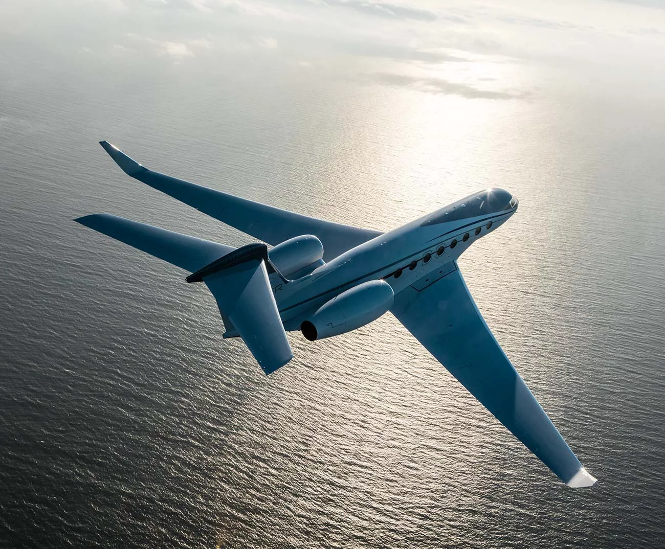Gulfstream G650ER in flight at sunset over mountainous terrain
